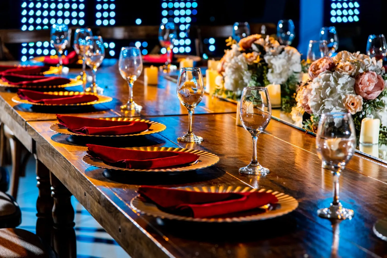 Mesa montada en rojo y dorado con velas y flores frente a la pista iluminada, en una fiesta de noche en Bonanza