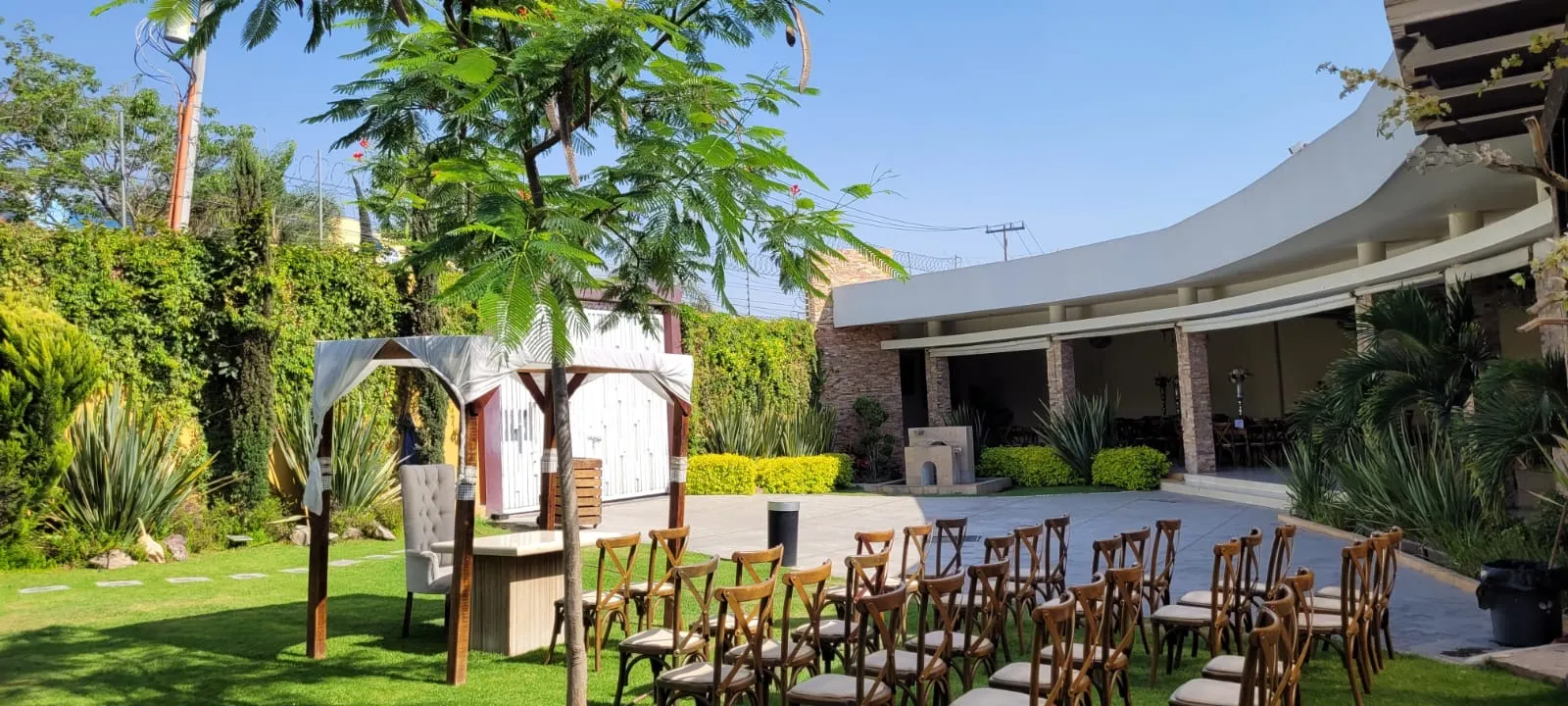Vista del jardín con pérgola y sillas de ceremonia frente al salón techado de Bonanza